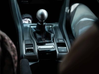 A closeup of a black modern manual car transmission gear shifter